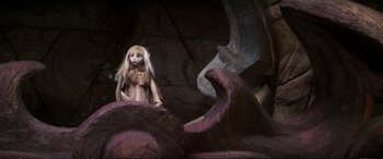 Movie still from “The Dark Crystal” (1982), directed by Frank Oz – A doll is sitting in a cave near some rocks; Wide shot, High angle
