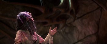 Movie still from “The Dark Crystal” (1982), directed by Frank Oz – A person with long black hair is holding their hands up; Close Up shot, Over the shoulder angle