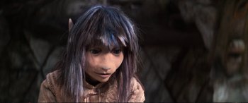 Movie still from “The Dark Crystal” (1982), directed by Frank Oz – A young girl with purple and blue hair looking at the camera; Close Up shot, High angle