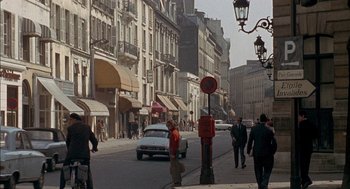 Movie still from “The Day of the Jackal” (1973), directed by Fred Zinnemann – A street scene with people walking on the sidewalk and cars driving on the street; Extreme Wide shot, High angle