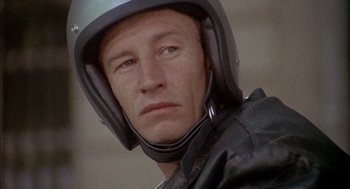 Movie still from “The Day of the Jackal” (1973), directed by Fred Zinnemann – A person wearing a motorcycle helmet; Close Up shot, Low angle