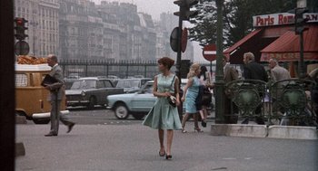 Movie still from “The Day of the Jackal” (1973), directed by Fred Zinnemann – A woman in a blue dress walking down a street; Wide shot, Low angle