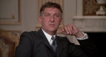 Movie still from “The Day of the Jackal” (1973), directed by Fred Zinnemann – A person wearing a suit and tie; Close Up shot, Low angle