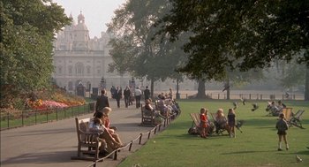 Movie still from “The Day of the Jackal” (1973), directed by Fred Zinnemann – A group of people sitting on park benches near trees; Extreme Wide shot, High angle