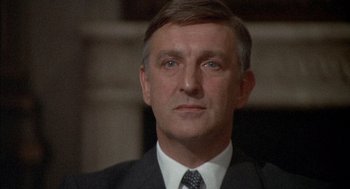Movie still from “The Day of the Jackal” (1973), directed by Fred Zinnemann – A person wearing a suit and tie; Close Up shot, Low angle
