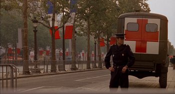 Movie still from “The Day of the Jackal” (1973), directed by Fred Zinnemann – A police officer standing on the side of the street; Wide shot, Low angle