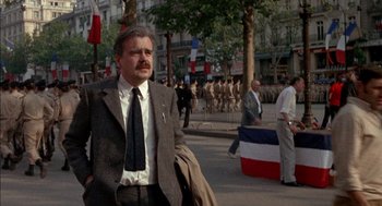 Movie still from “The Day of the Jackal” (1973), directed by Fred Zinnemann – A man in a suit and tie walking down a street; Medium shot, Low angle