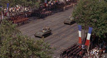 Movie still from “The Day of the Jackal” (1973), directed by Fred Zinnemann – Two tanks are driving down the street in front of a crowd; Extreme Wide shot, High angle