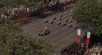 Movie still from “The Day of the Jackal” (1973), directed by Fred Zinnemann – An aerial view of a military parade in a city; Extreme Wide shot, High angle