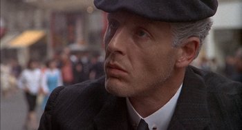 Movie still from “The Day of the Jackal” (1973), directed by Fred Zinnemann – A person wearing a suit and a hat; Close Up shot, Over the shoulder angle