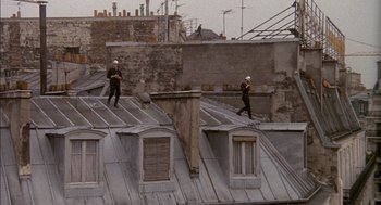 Movie still from “The Day of the Jackal” (1973), directed by Fred Zinnemann – Two roofers are standing on the roof of a building; Wide shot, High angle