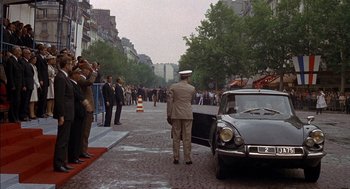 Movie still from “The Day of the Jackal” (1973), directed by Fred Zinnemann – A crowd of people standing around a car on a street; Wide shot, High angle
