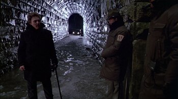 Movie still from “The Dead Zone” (1983), directed by David Cronenberg – Two men in winter coats are standing in an underground tunnel; Wide shot, Low angle