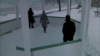 Movie still from “The Dead Zone” (1983), directed by David Cronenberg – Three people are standing in the snow near a gazebo; Wide shot, High angle