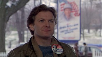 Movie still from “The Dead Zone” (1983), directed by David Cronenberg – A man wearing a jacket and a button with an image on it; Close Up shot, Low angle