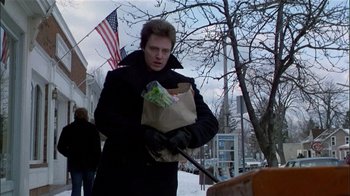 Movie still from “The Dead Zone” (1983), directed by David Cronenberg – A man holding a bag of food on the sidewalk; Medium shot, Low angle