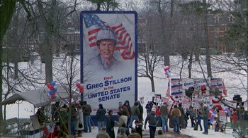 Movie still from “The Dead Zone” (1983), directed by David Cronenberg – A crowd of people standing next to a large sign; Wide shot, High angle