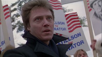 Movie still from “The Dead Zone” (1983), directed by David Cronenberg – A man in a black jacket is standing in front of political signs; Close Up shot, Low angle