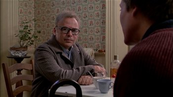 Movie still from “The Dead Zone” (1983), directed by David Cronenberg – A man sitting at a table with a cup of coffee; Medium shot, Over the shoulder angle