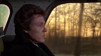 Movie still from “The Dead Zone” (1983), directed by David Cronenberg – A man sitting in the passenger seat of a car looking out the window; Close Up shot, Low angle