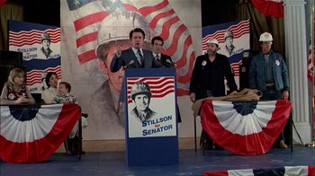 Movie still from “The Dead Zone” (1983), directed by David Cronenberg – A man standing in front of an american flag; Medium shot, Low angle