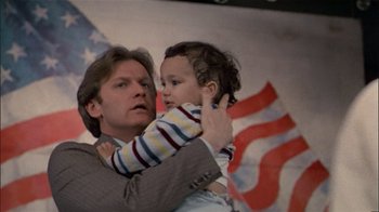 Movie still from “The Dead Zone” (1983), directed by David Cronenberg – A man holding a child in his arms; Medium shot, Low angle