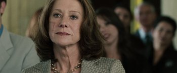 Movie still from “The Debt” (2010), directed by John Madden – An older woman wearing a gray jacket and a necklace; Close Up shot, Low angle