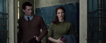 Movie still from “The Debt” (2010), directed by John Madden – A man and a woman standing next to each other in a room; Medium shot, Low angle