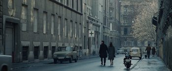 Movie still from “The Debt” (2010), directed by John Madden – Two people walking down a street near some buildings; Wide shot, High angle
