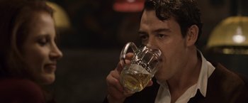 Movie still from “The Debt” (2010), directed by John Madden – A man is drinking a glass of beer from a mug; Close Up shot, Over the shoulder angle