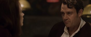 Movie still from “The Debt” (2010), directed by John Madden – A person wearing a suit and tie; Close Up shot, Low angle