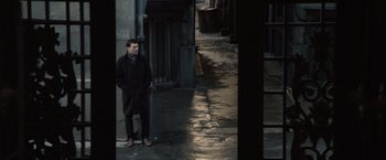 Movie still from “The Debt” (2010), directed by John Madden – A man standing in the middle of an alleyway; Wide shot, High angle