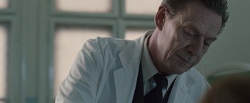 Movie still from “The Debt” (2010), directed by John Madden – A person wearing a suit and tie; Close Up shot, Low angle