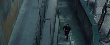 Movie still from “The Debt” (2010), directed by John Madden – A man running up a flight of stairs in the dark; Extreme Wide shot, High angle