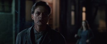 Movie still from “The Debt” (2010), directed by John Madden – A man smoking a cigarette while looking at the camera; Close Up shot, Low angle