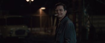 Movie still from “The Debt” (2010), directed by John Madden – A man is standing in the dark with a cigarette in his mouth; Close Up shot, Over the shoulder angle