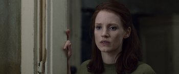 Movie still from “The Debt” (2010), directed by John Madden – A woman holding a wooden stick in front of a wall; Close Up shot, Over the shoulder angle