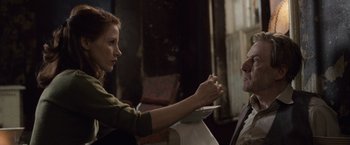 Movie still from “The Debt” (2010), directed by John Madden – A woman sitting next to a man holding a plate; Close Up shot, Over the shoulder angle