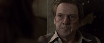 Movie still from “The Debt” (2010), directed by John Madden – An older man with a beard and mustache looking at the camera; Close Up shot, Over the shoulder angle