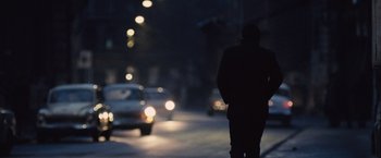 Movie still from “The Debt” (2010), directed by John Madden – A person walking down a street at night; Wide shot, Over the shoulder angle