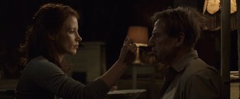Movie still from “The Debt” (2010), directed by John Madden – A woman feeding a man a piece of food from a spoon; Medium shot, Low angle