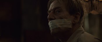 Movie still from “The Debt” (2010), directed by John Madden – A man with his mouth taped shut and looking to his left; Close Up shot, Low angle