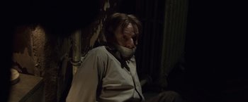 Movie still from “The Debt” (2010), directed by John Madden – A man with his mouth taped shut sitting in a dark room; Close Up shot, Over the shoulder angle