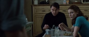 Movie still from “The Debt” (2010), directed by John Madden – A man sitting at a table with a bowl of food; Medium shot, Over the shoulder angle