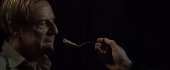Movie still from “The Debt” (2010), directed by John Madden – A person is holding a spoon in their mouth; Extreme Close Up shot, Over the shoulder angle
