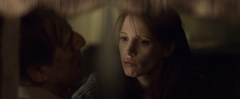 Movie still from “The Debt” (2010), directed by John Madden – A young woman with blue eyes looking at the camera; Close Up shot, Over the shoulder angle