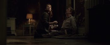 Movie still from “The Debt” (2010), directed by John Madden – A man and a woman sitting on the ground; Medium shot, Low angle