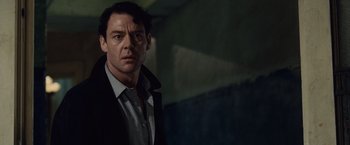 Movie still from “The Debt” (2010), directed by John Madden – A person wearing a suit and tie; Close Up shot, Low angle