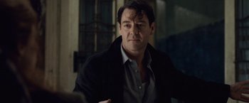 Movie still from “The Debt” (2010), directed by John Madden – A person wearing a jacket and a shirt; Close Up shot, Over the shoulder angle