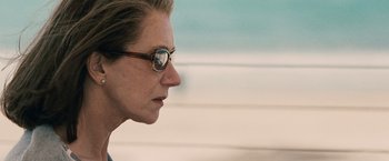 Movie still from “The Debt” (2010), directed by John Madden – A person wearing glasses and looking to the side; Close Up shot, Over the shoulder angle
